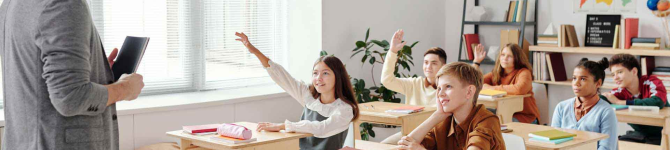 enfants dans une salle de classe levant la main pour répondre à la question de l'instituteur